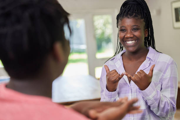 Teenage Girl And Boy Having Conversation Using Sign Language At Home